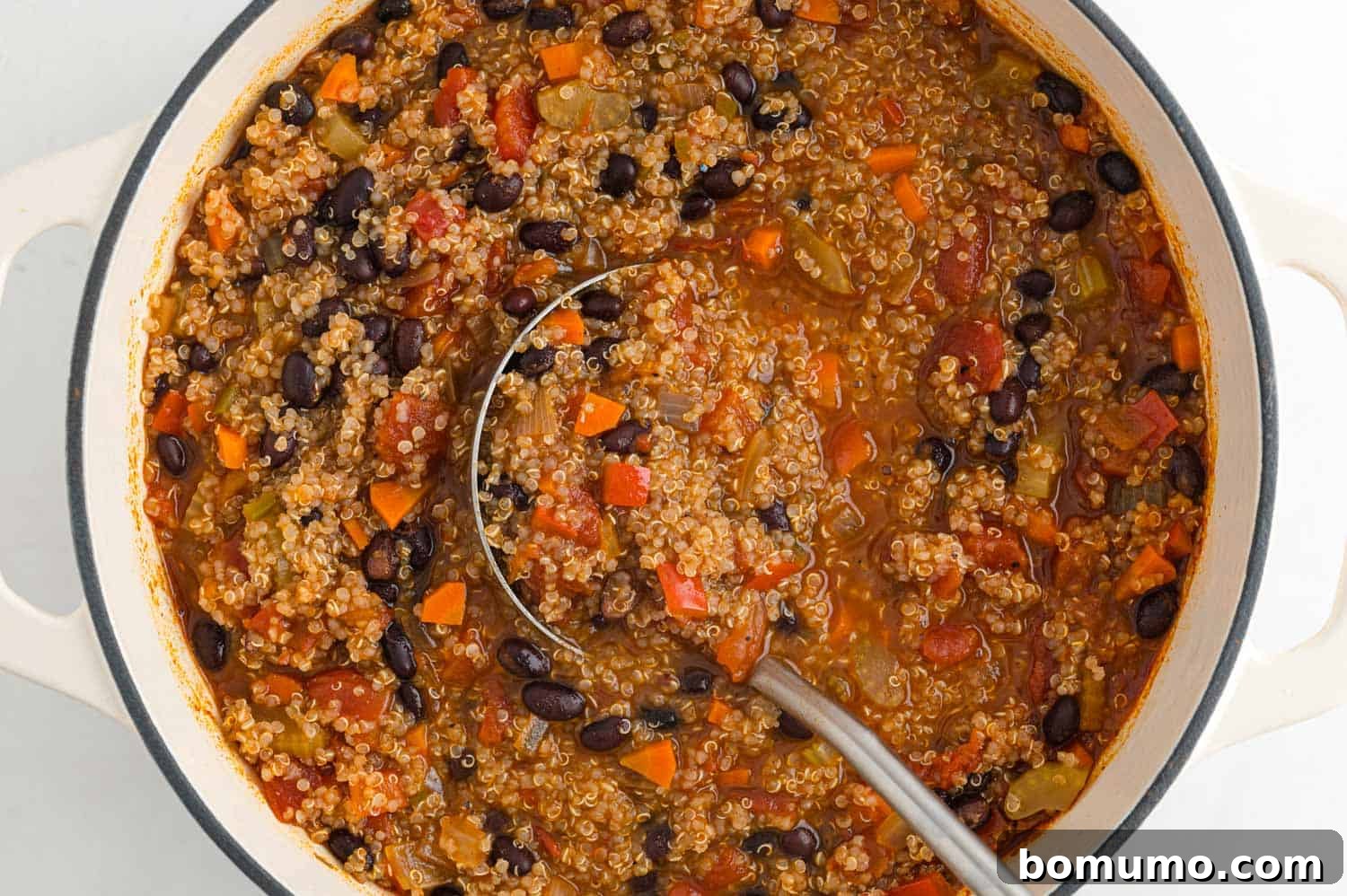 A large pot of perfectly cooked vegetarian quinoa chili, with a ladle resting inside, ready for serving.