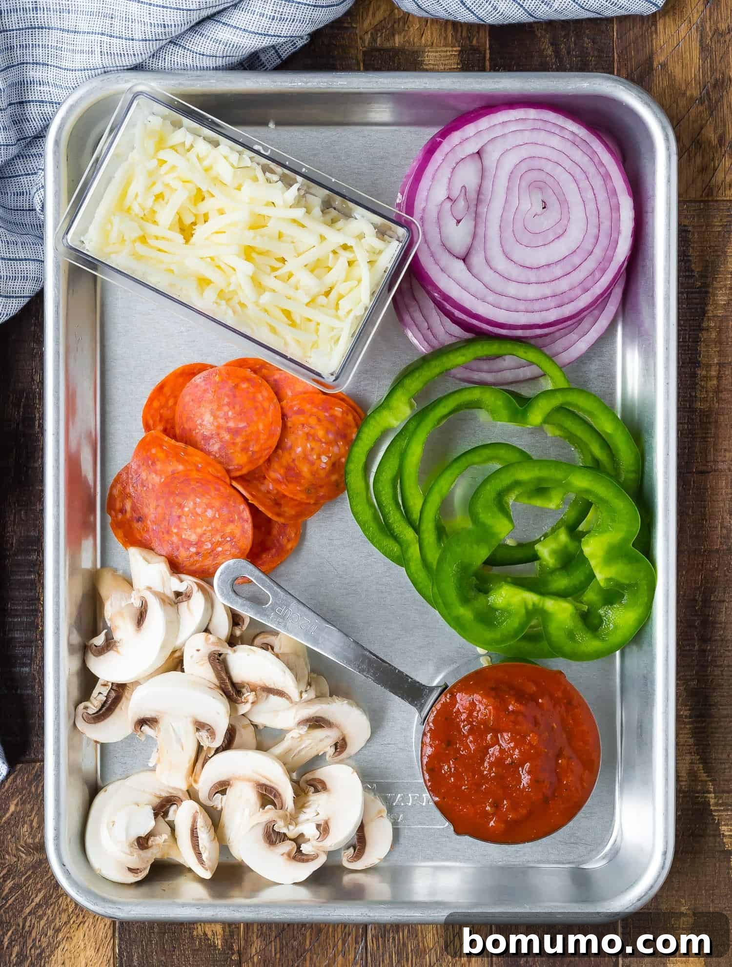 A vibrant assortment of classic pizza toppings, including mushrooms, onions, and pepperoni, neatly arranged on a sheet pan, ready for assembly.