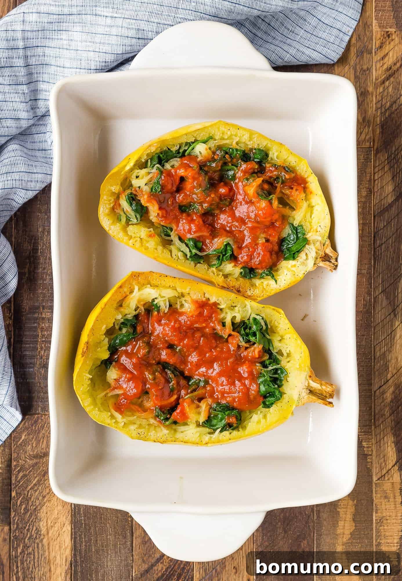 Rich, savory pizza sauce generously spread over the fluffy spaghetti squash strands in a baked squash half, forming the flavorful base for toppings.