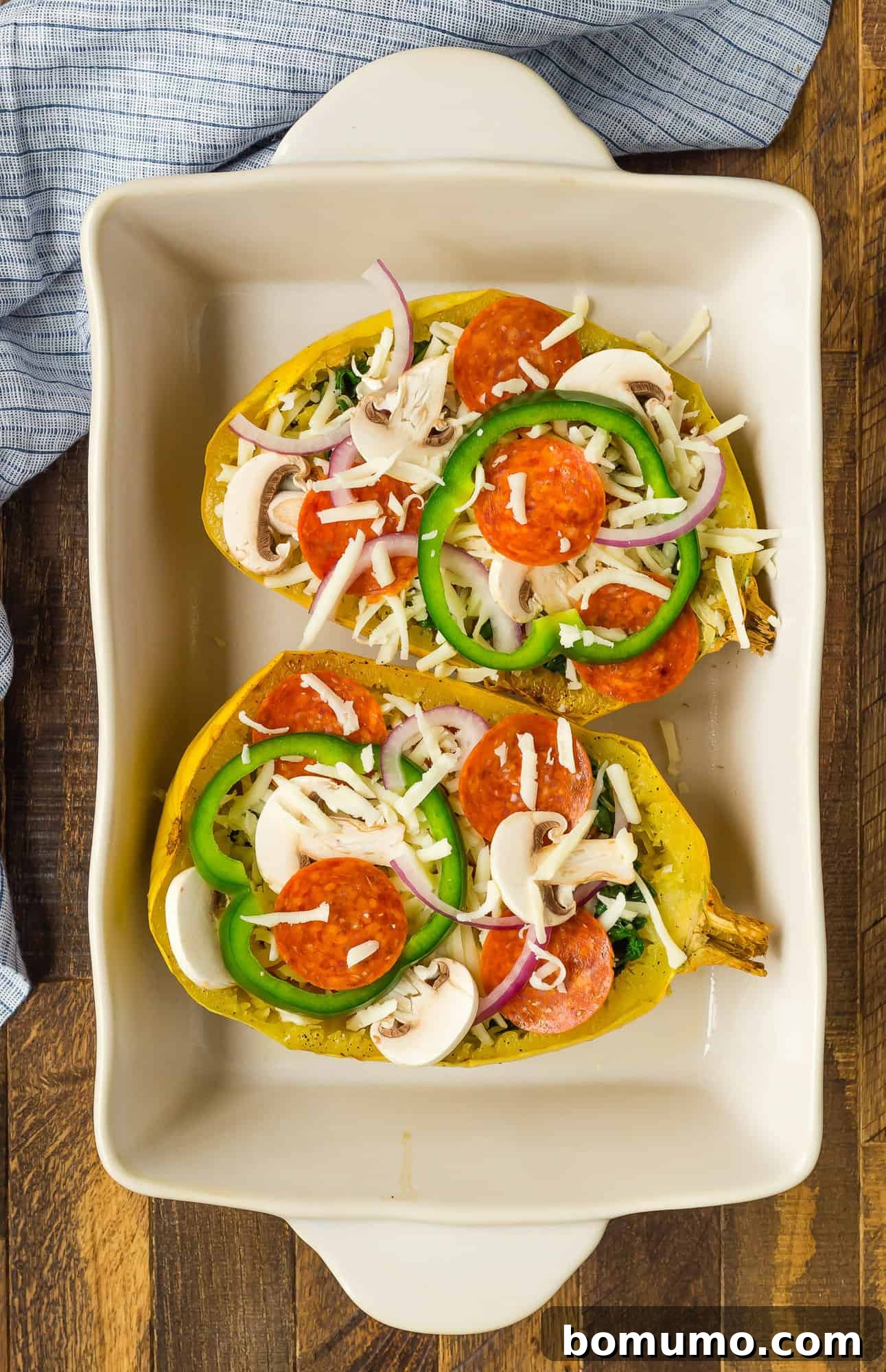 The fully assembled pizza stuffed spaghetti squash, richly topped with pepperoni, vegetables, and melted mozzarella, ready for its final broiling stage.