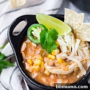 Image of pressure cooker white chili in a black bowl with garnishes.