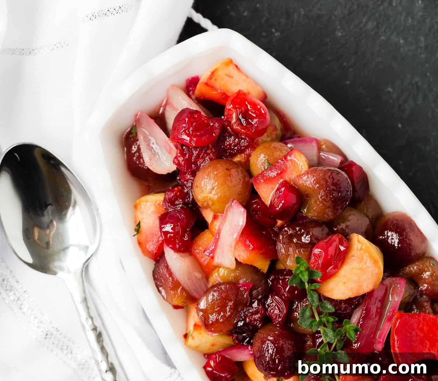 Overhead view of a beautifully presented cranberry grape and shallot sauce, garnished with fresh herbs, ready for serving.