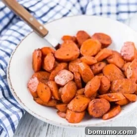 Glazed carrots in a bowl, sprinkled with fresh herbs.