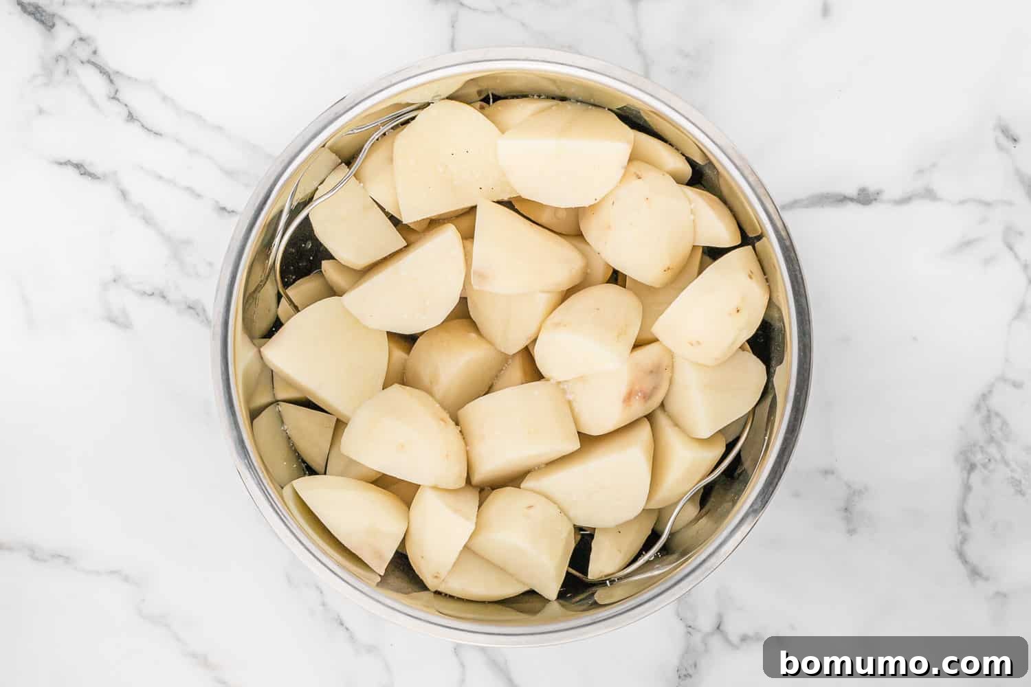 Uncooked, peeled, and chunked potatoes placed on a wire trivet inside an Instant Pot.