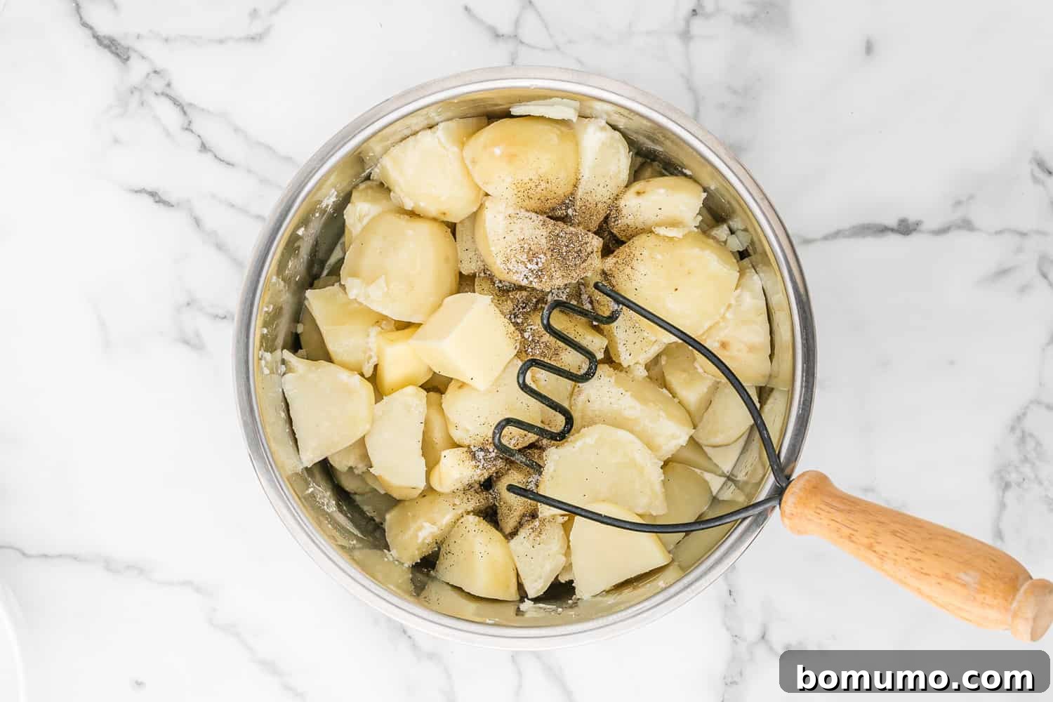 Potatoes partially mashed in the Instant Pot with a potato masher.