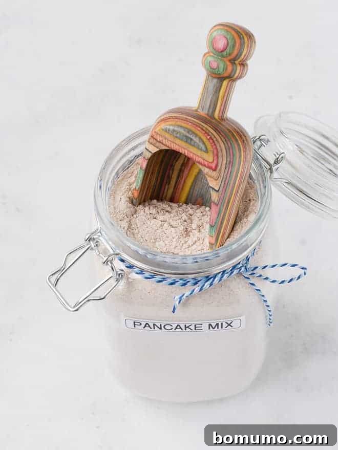 Image of dry pancake mix with a scoop inside a clear storage jar, ready to be used.