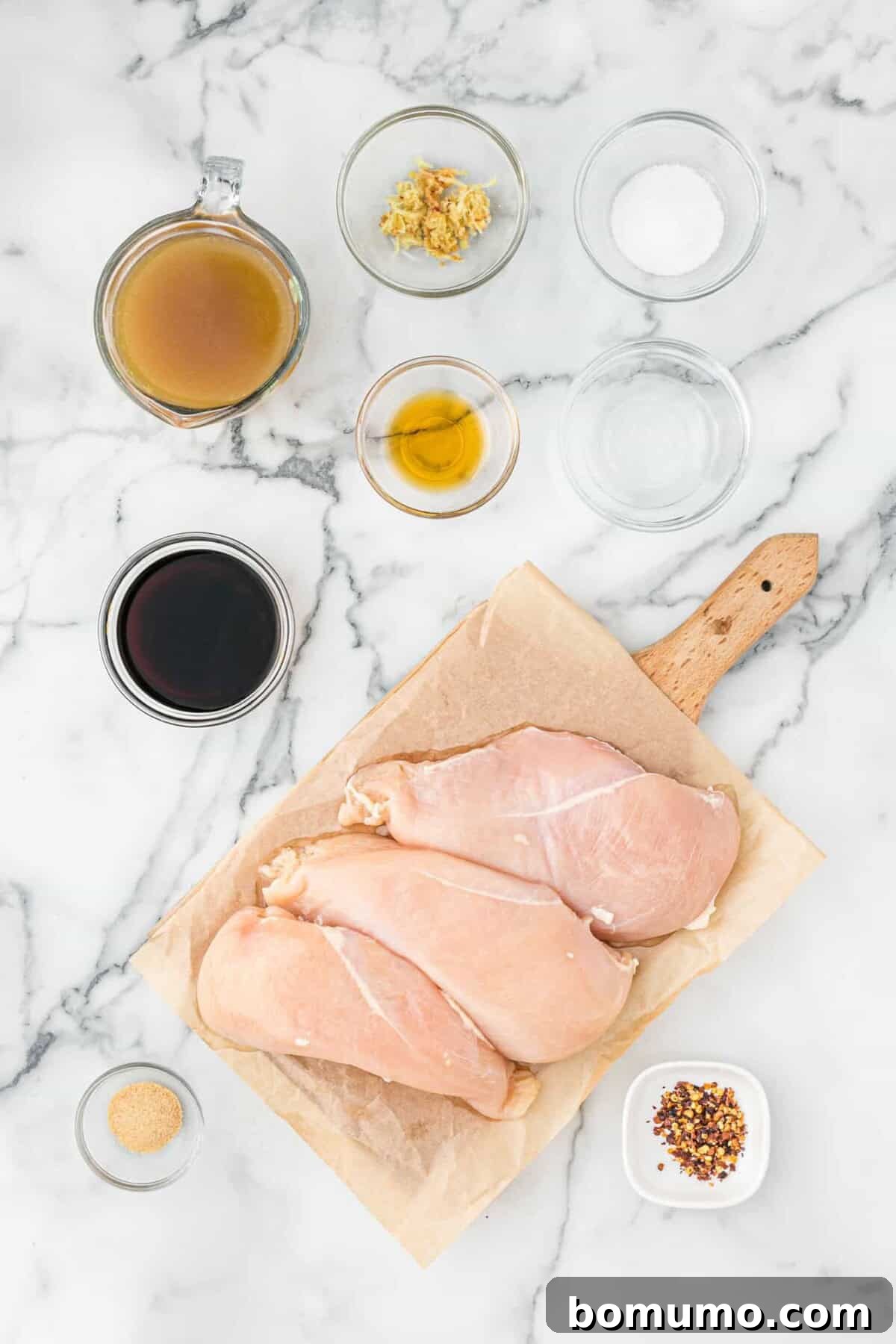Fresh ingredients laid out, including raw chicken breasts, ready for marinating.