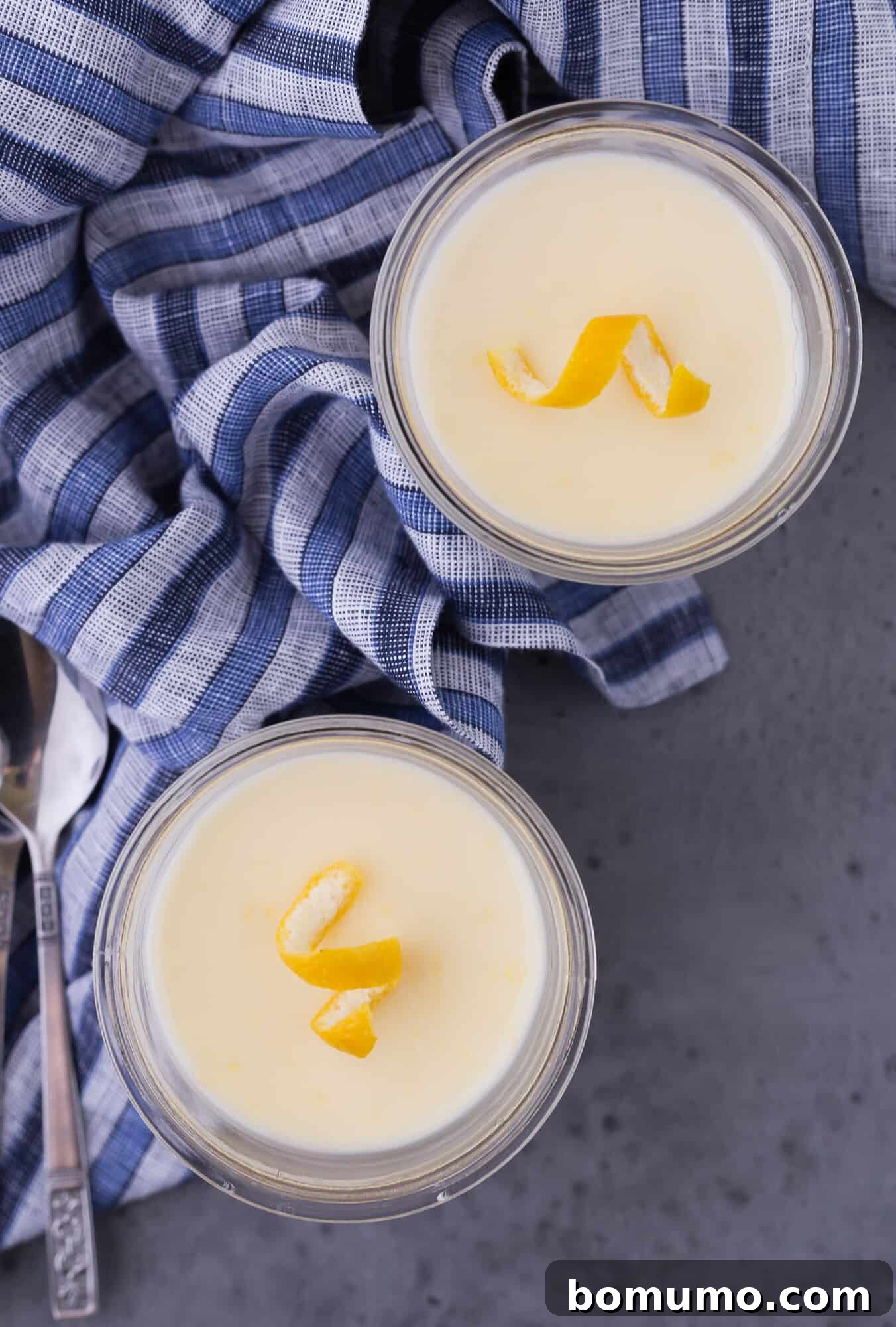 Easy 3-Ingredient Lemon Pudding 2 Two exquisite servings of creamy lemon pudding, garnished with lemon twists, presented in elegant dessert cups.