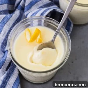 Easy 3-Ingredient Lemon Pudding 7 A small jar of lemon pudding, garnished with a lemon twist and a spoon, ready to be enjoyed.