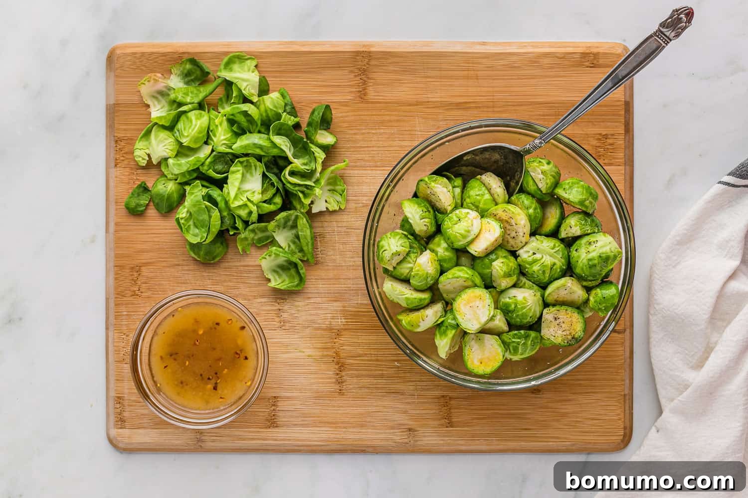 Freshly prepped Brussels sprouts being tossed in a mixing bowl with olive oil and seasonings, ready for the air fryer.