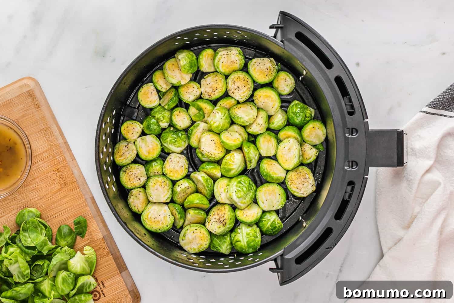 Brussels sprouts arranged in a single, even layer within the air fryer basket, prior to cooking, ensuring even crisping.