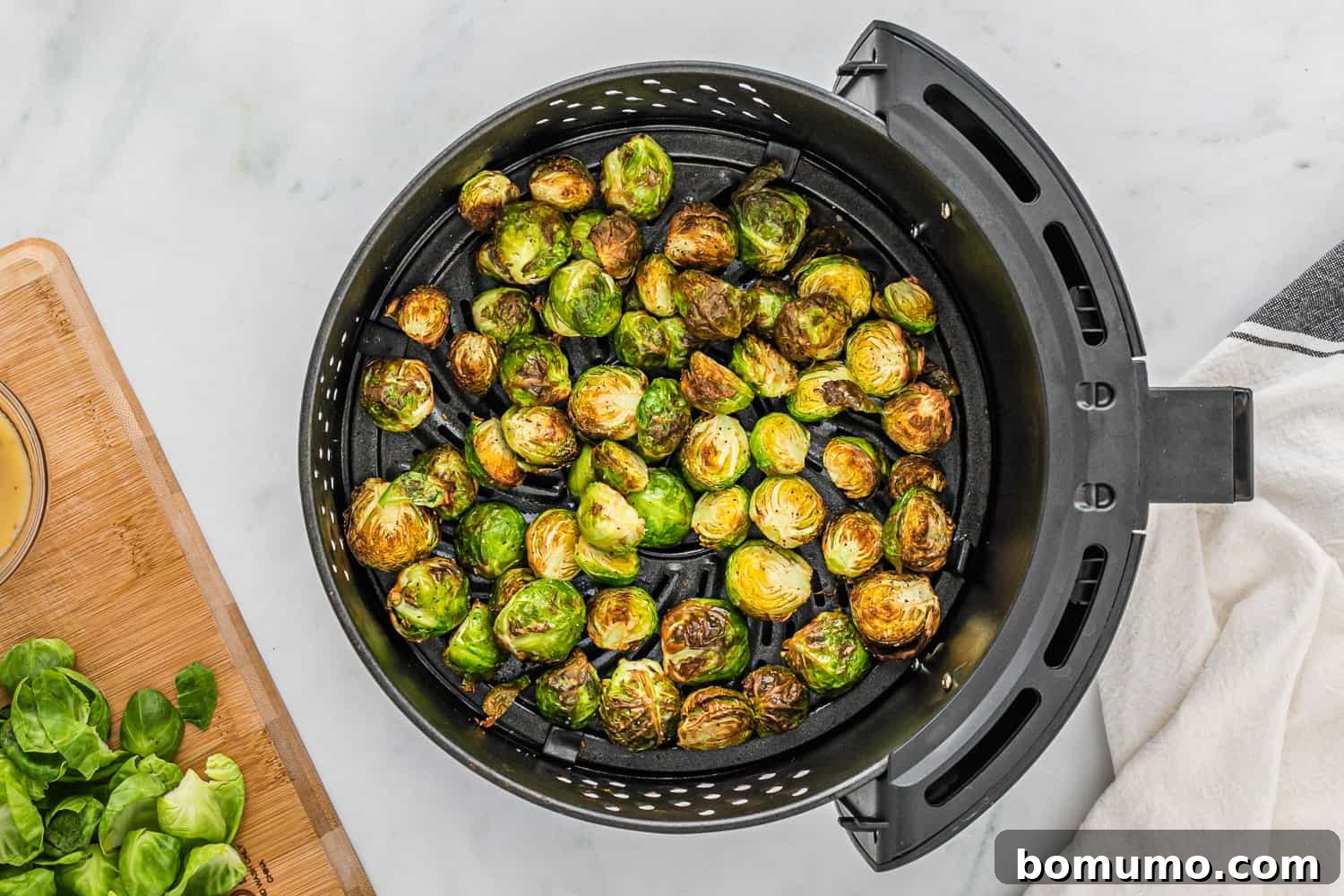 Perfectly cooked, golden-brown Brussels sprouts glistening in the air fryer basket after being cooked to crispy perfection.