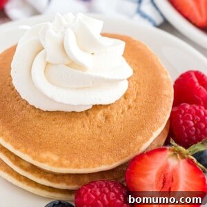 Whipped cream piped onto a small stack of pancakes, a delightful topping.