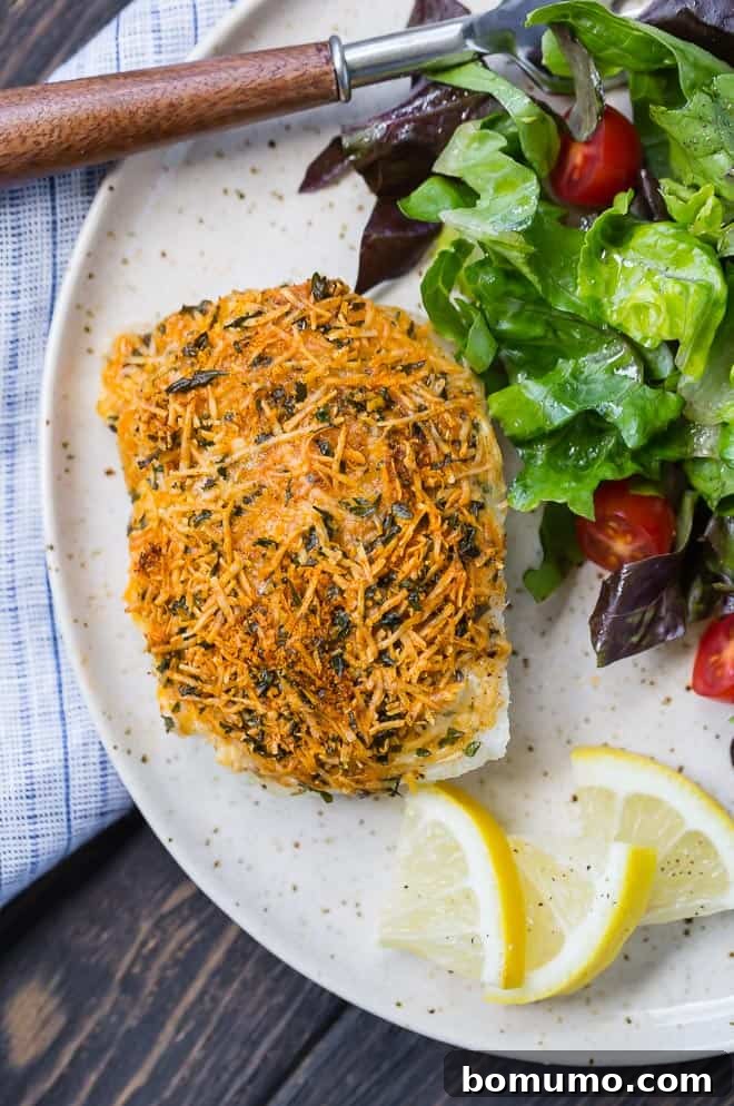 Golden-brown parmesan baked cod fillets, perfectly crispy and ready to serve on a white dish with a fresh lemon wedge.