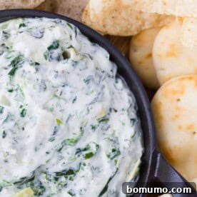Close-up of a bubbling slow cooker spinach artichoke dip, a classic warm appetizer.
