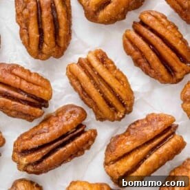 Spiced pecans scattered on a clean white background, showcasing their delicious coating.