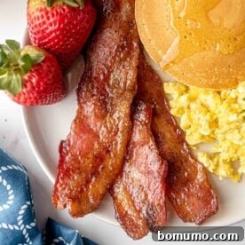 Candied bacon on a plate, gleaming with its sweet glaze, a truly addictive treat.