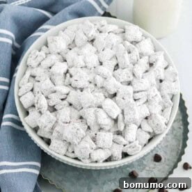 A large bowl of puppy chow (muddy buddies) coated in powdered sugar, a fun and irresistible snack.