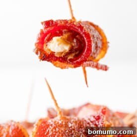 A bacon-wrapped date held aloft, showcasing its crispy exterior, a perfect sweet and savory bite.