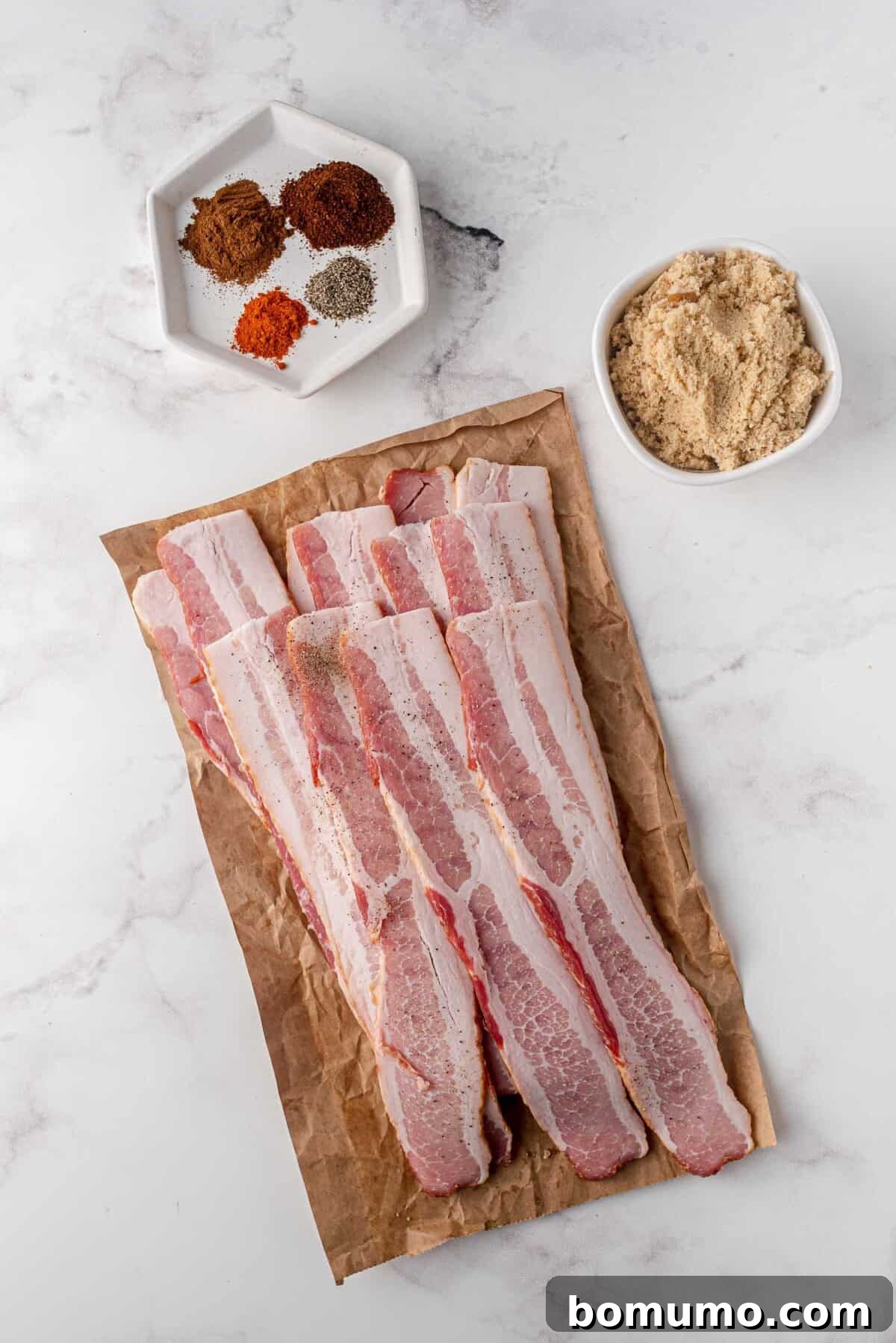 An overhead view of the essential ingredients laid out for making candied bacon, including bacon, brown sugar, and spices.