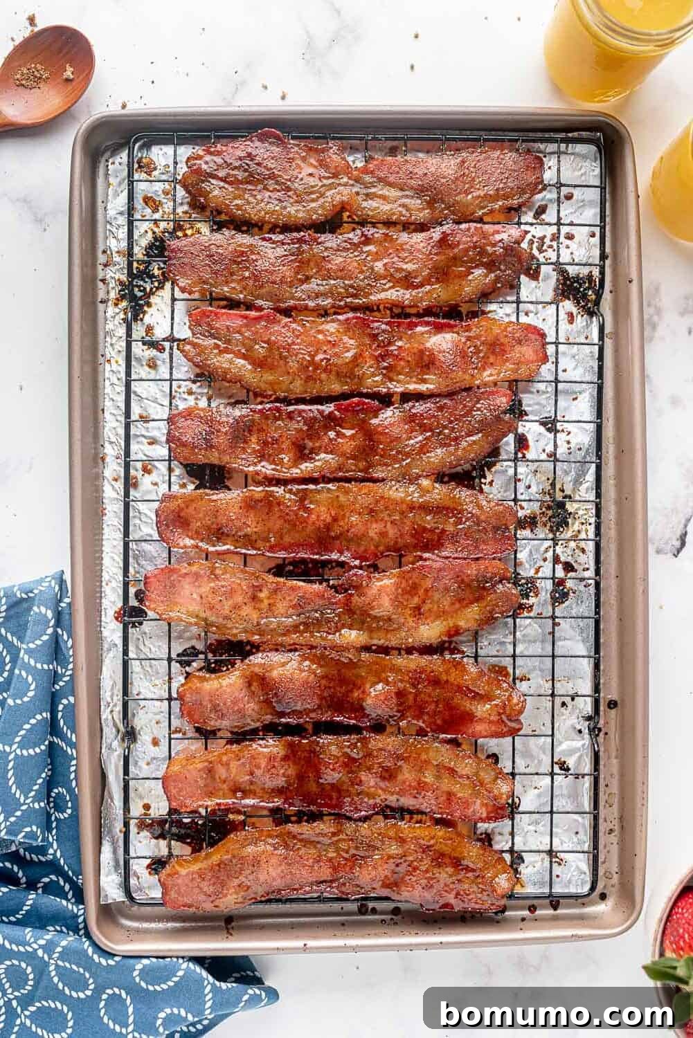 Golden-brown, freshly baked candied bacon strips cooling on a wire rack, ready to crisp up.