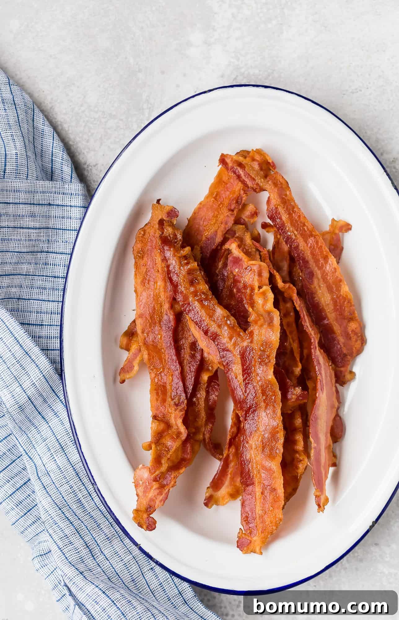 A vibrant white and blue patterned plate overflowing with perfectly cooked crispy bacon, showcasing its inviting texture.