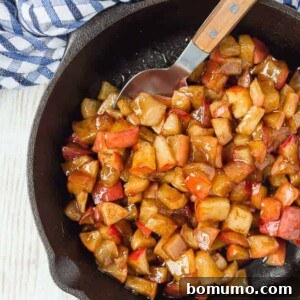 Apple compote in a cast iron skillet, with a spoon.