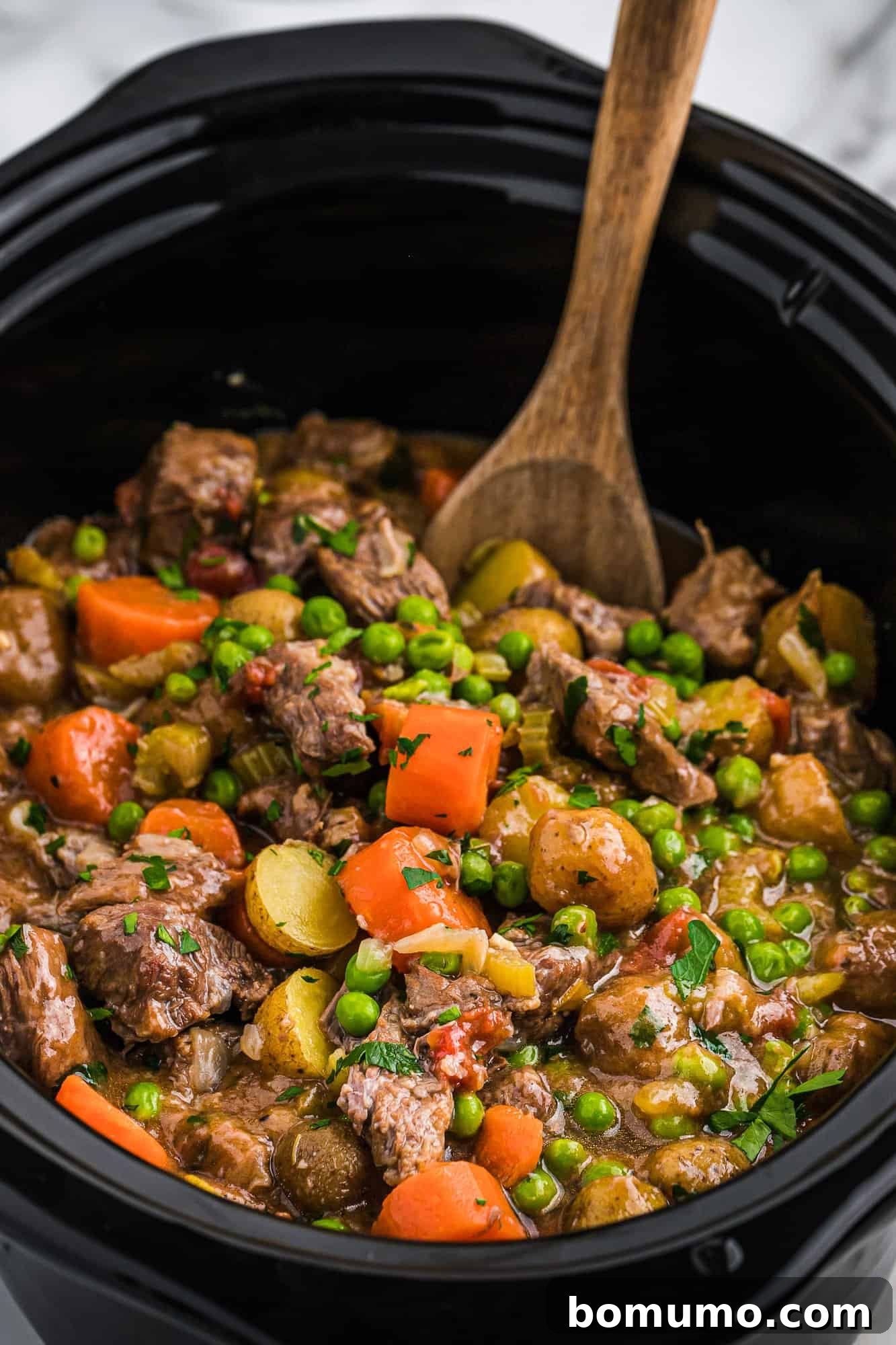 Close-up view of beef stew simmering inside a crockpot, highlighting the rich texture and ingredients.