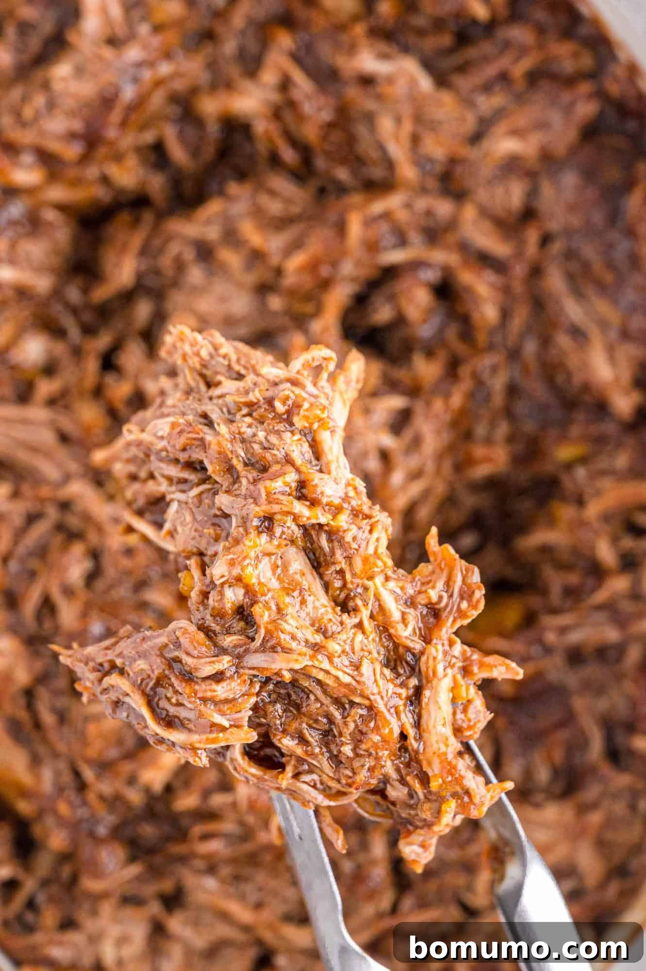 Pulled pork on tongs.
