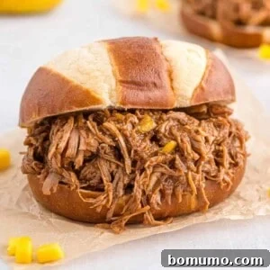 Pulled pork on a pretzel bun on natural colored parchment paper.