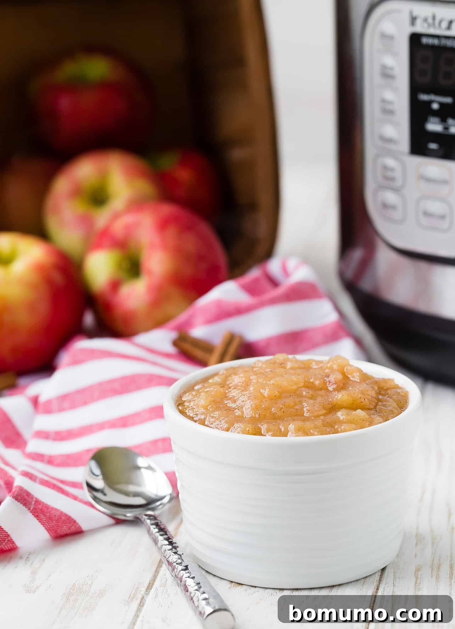 Simple Instant Pot Applesauce 4 A bowl of pressure cooker applesauce in the foreground, with an Instant Pot visible in the soft focus background.