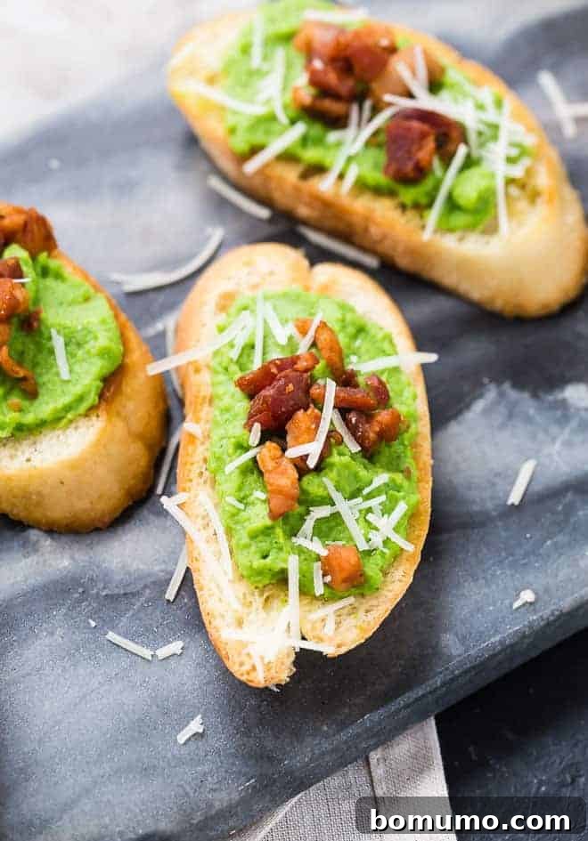 Close-up image of creamy pea puree spread on crispy bread slices, garnished with finely diced crispy pancetta and a generous sprinkle of Parmesan cheese, ready to be served as an appetizer.