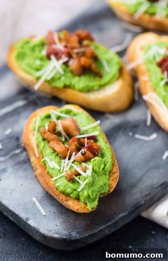 Close-up image of vibrant green pureed peas being spooned onto a slice of golden-brown crostini, showcasing the smooth, creamy texture of the pea spread.