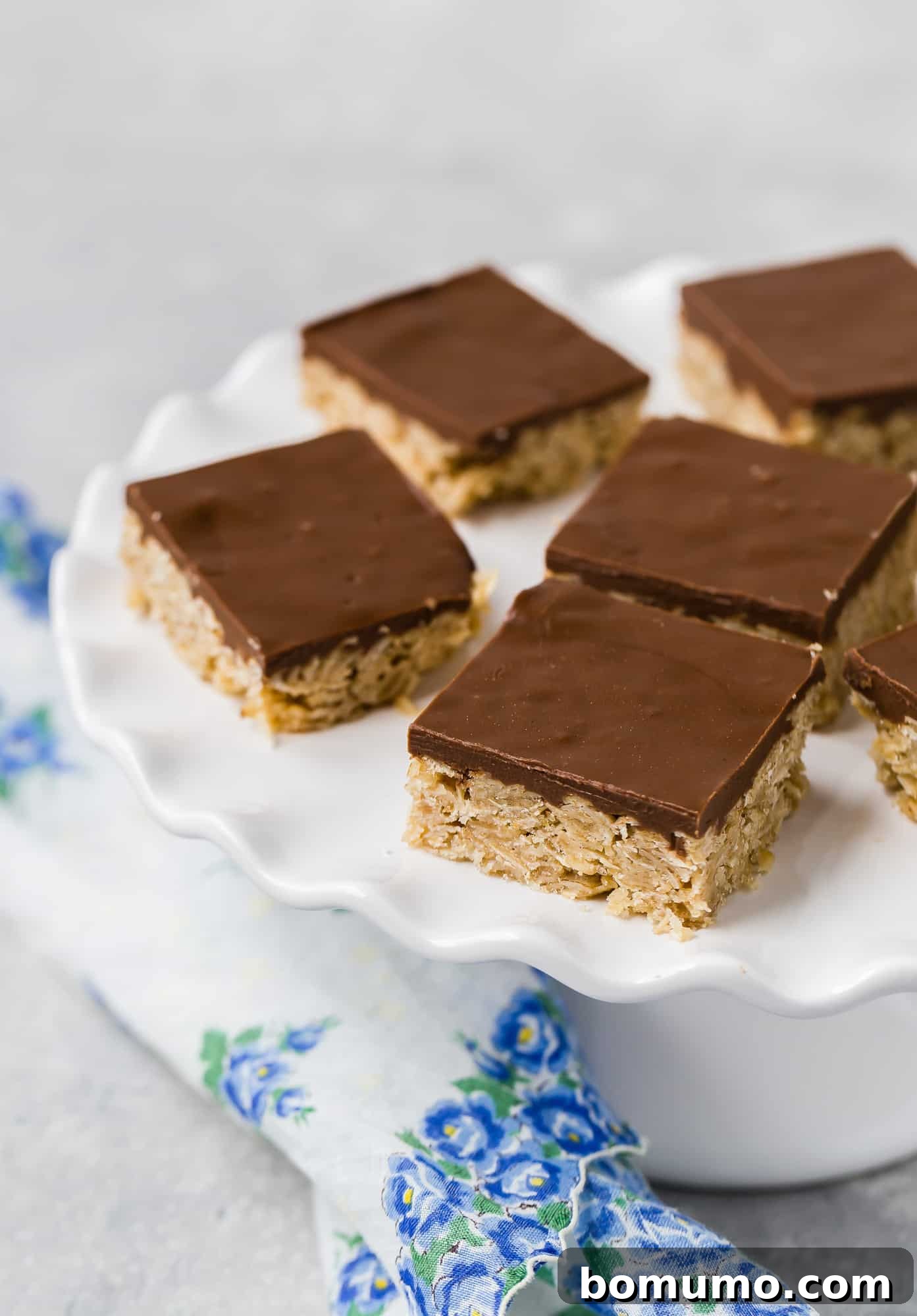 Oh Henry Bars Nut-Free Version Available 3 Oat and chocolate bars on a white cake stand, neatly arranged.