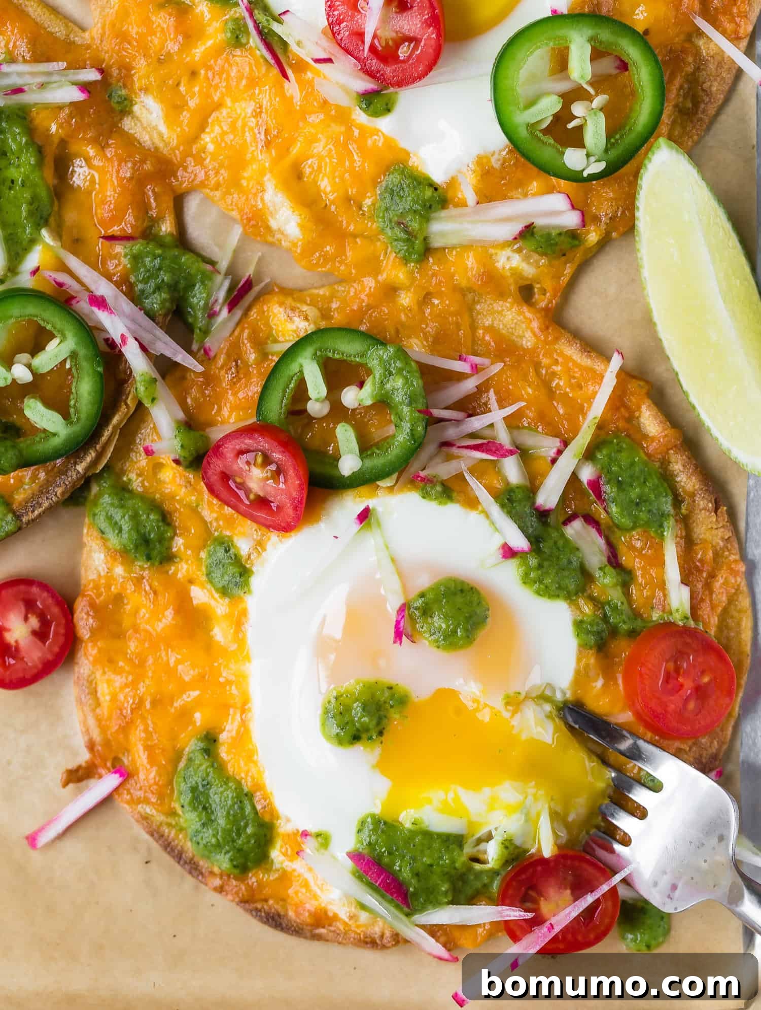One-Pan Breakfast Tostadas 6 The moment a fork breaks into the runny yolk of an egg on a breakfast tostada, revealing its rich, golden interior, surrounded by melted cheese and vibrant toppings.