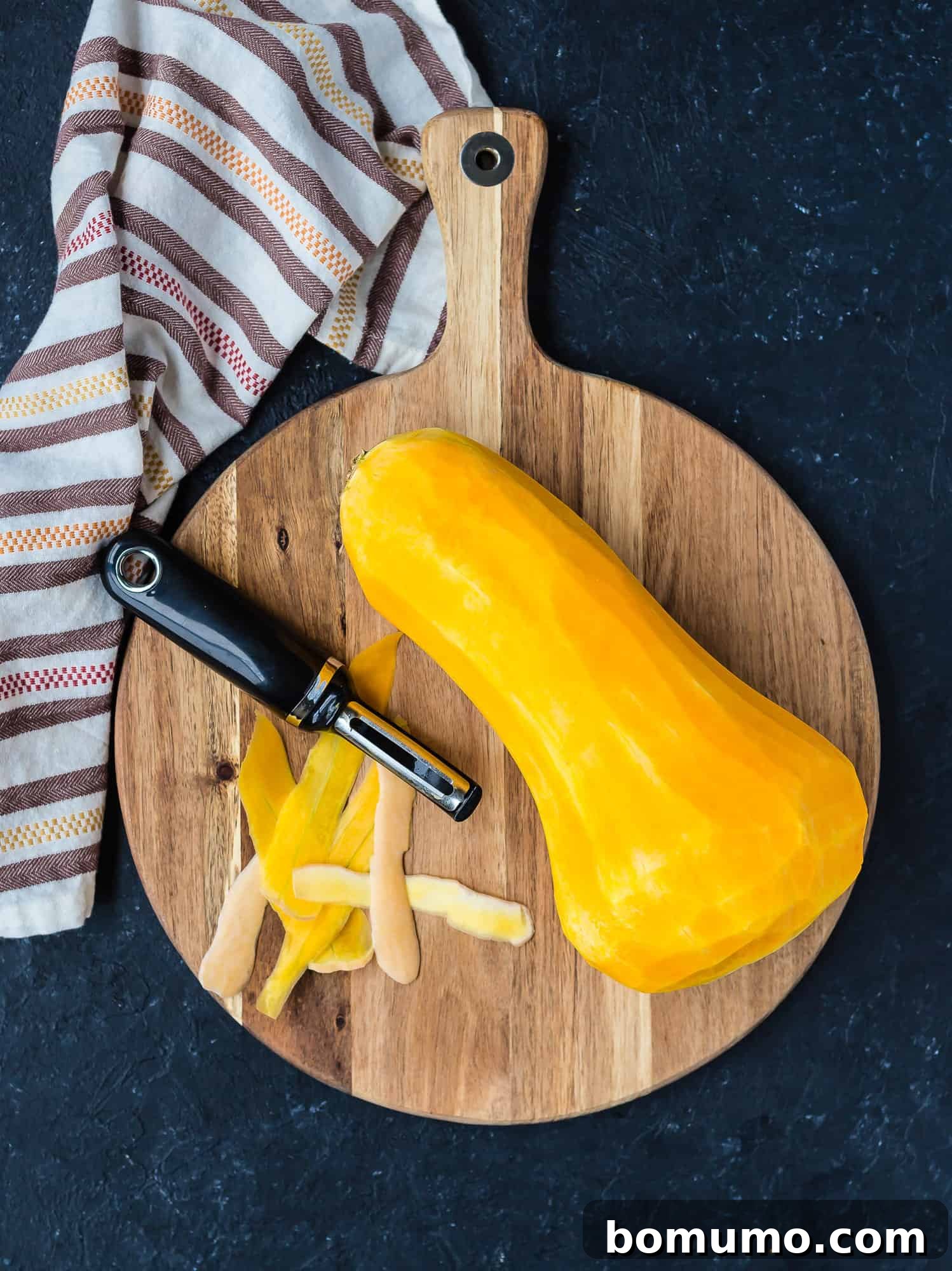 A butternut squash, perfectly peeled, revealing its smooth, bright orange flesh.