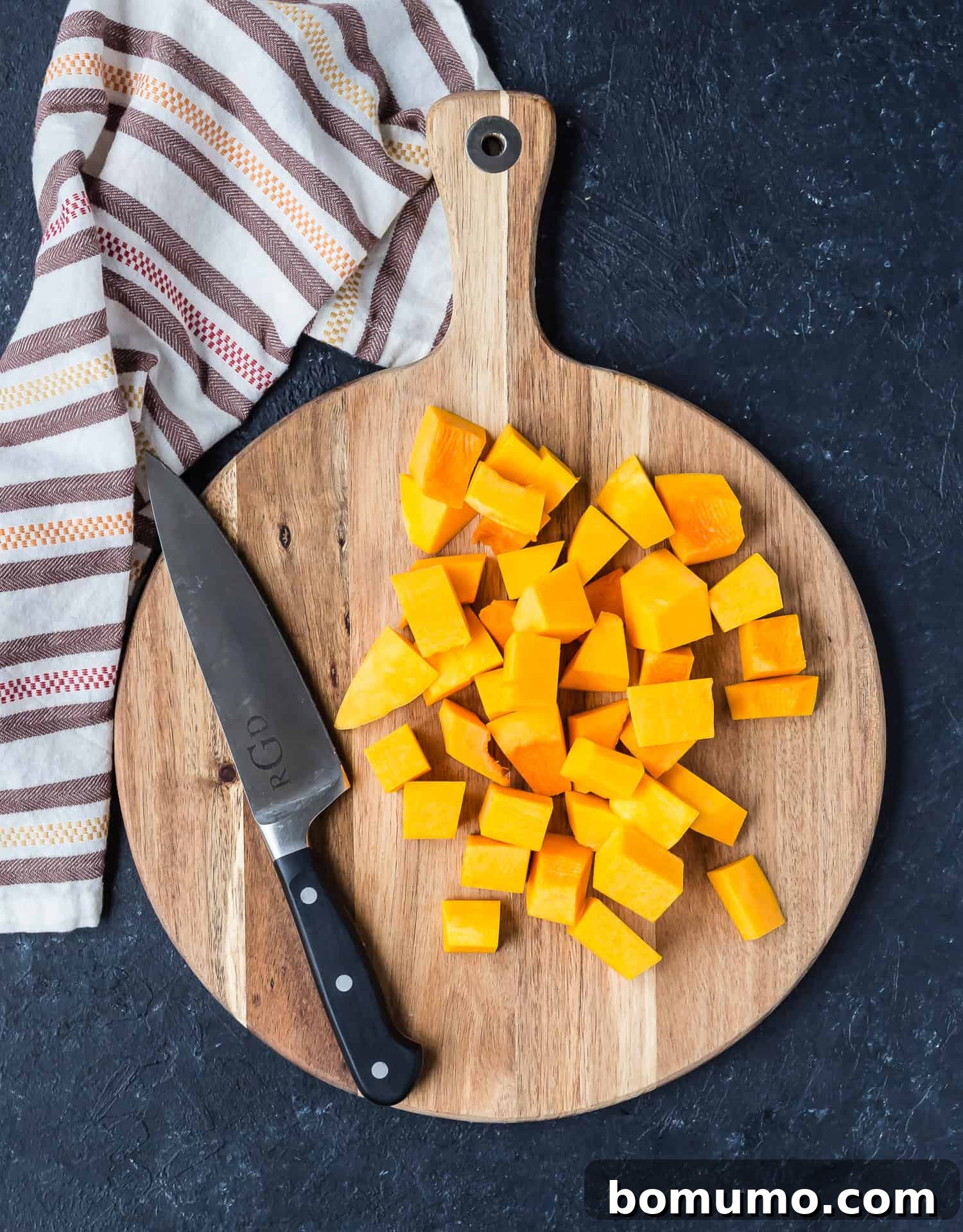 Neatly diced butternut squash cubes, ready for cooking, spread out on a cutting board.