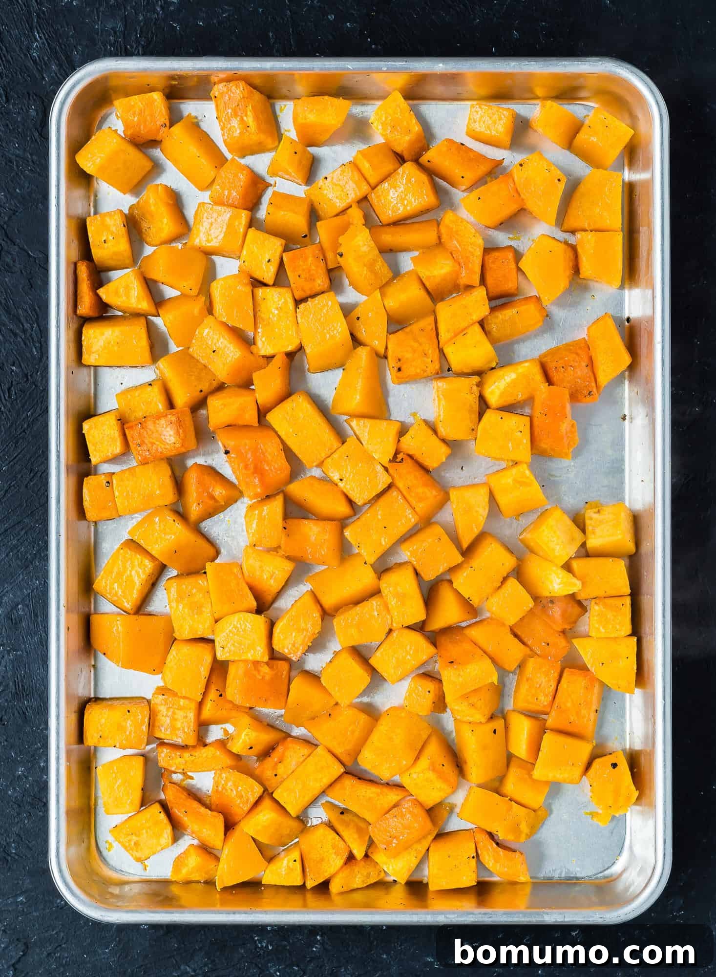 Perfectly roasted and golden brown butternut squash cubes on a sheet pan, ready to be served.
