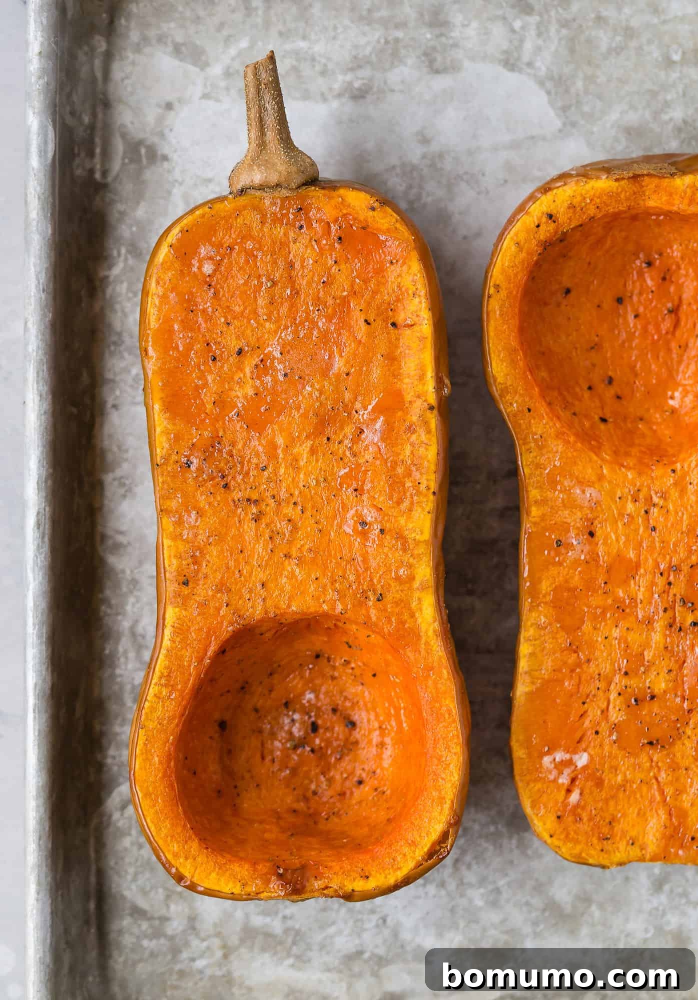 Two halves of roasted butternut squash, cooked to perfection, with golden-brown edges.