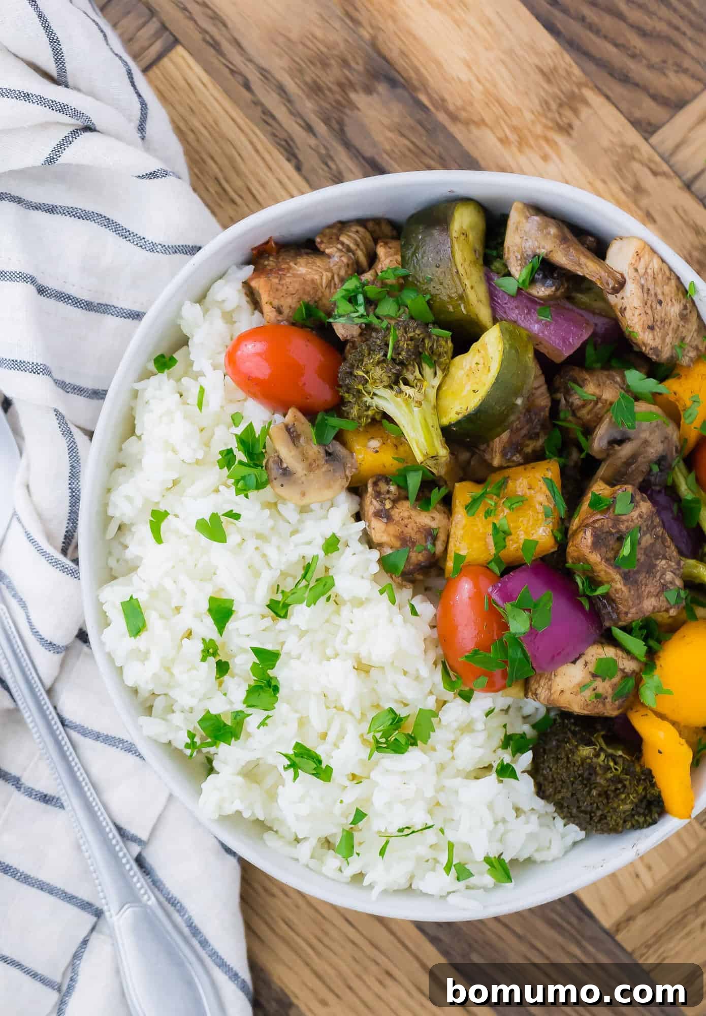 Balsamic chicken and vegetables with rice served in a white bowl.