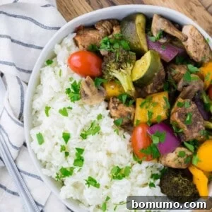 Chicken, vegetables, and rice in a bowl, showcasing the final dish.