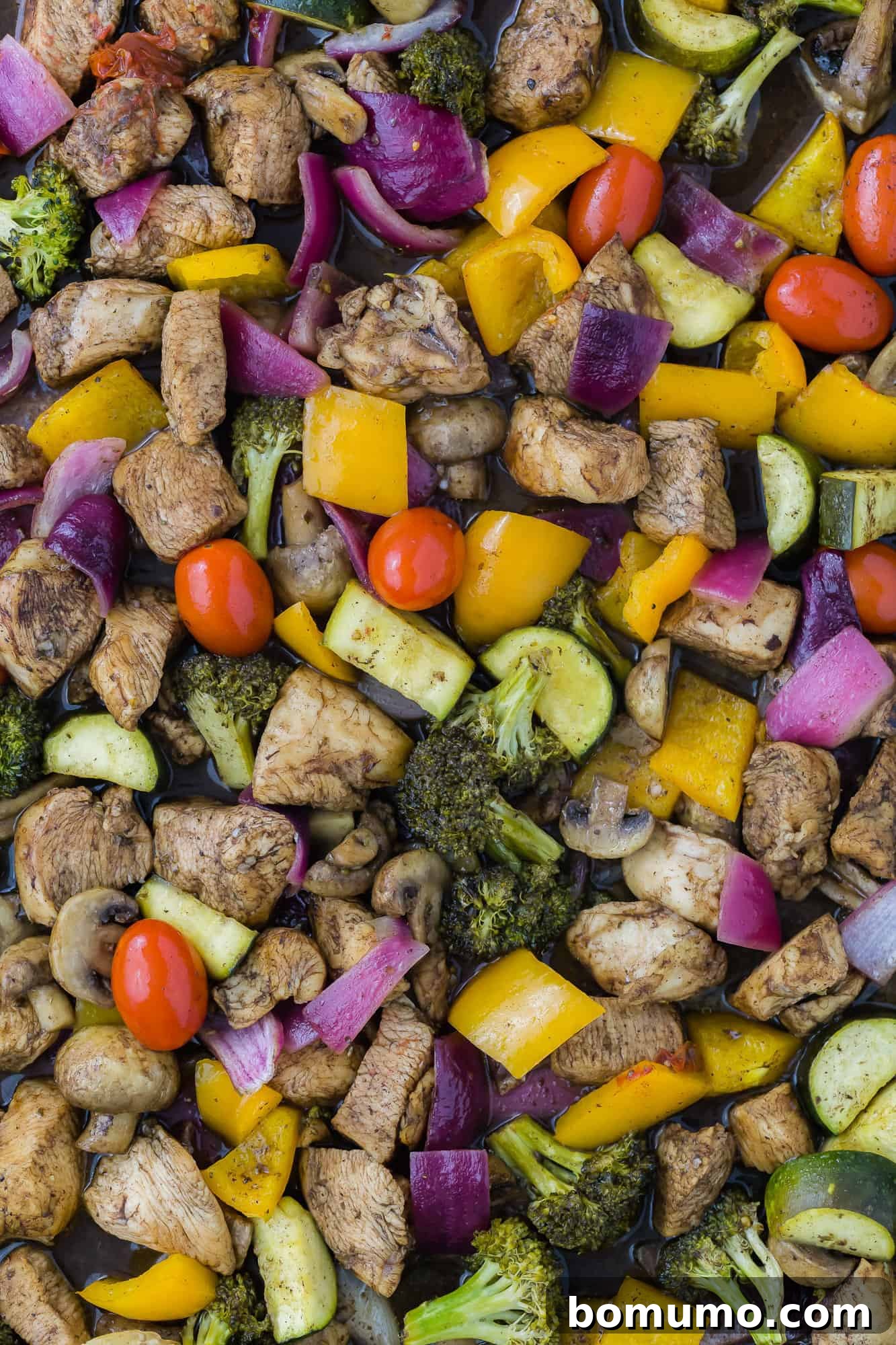 Chicken and vegetables with balsamic sauce on a sheet pan, ready to serve.