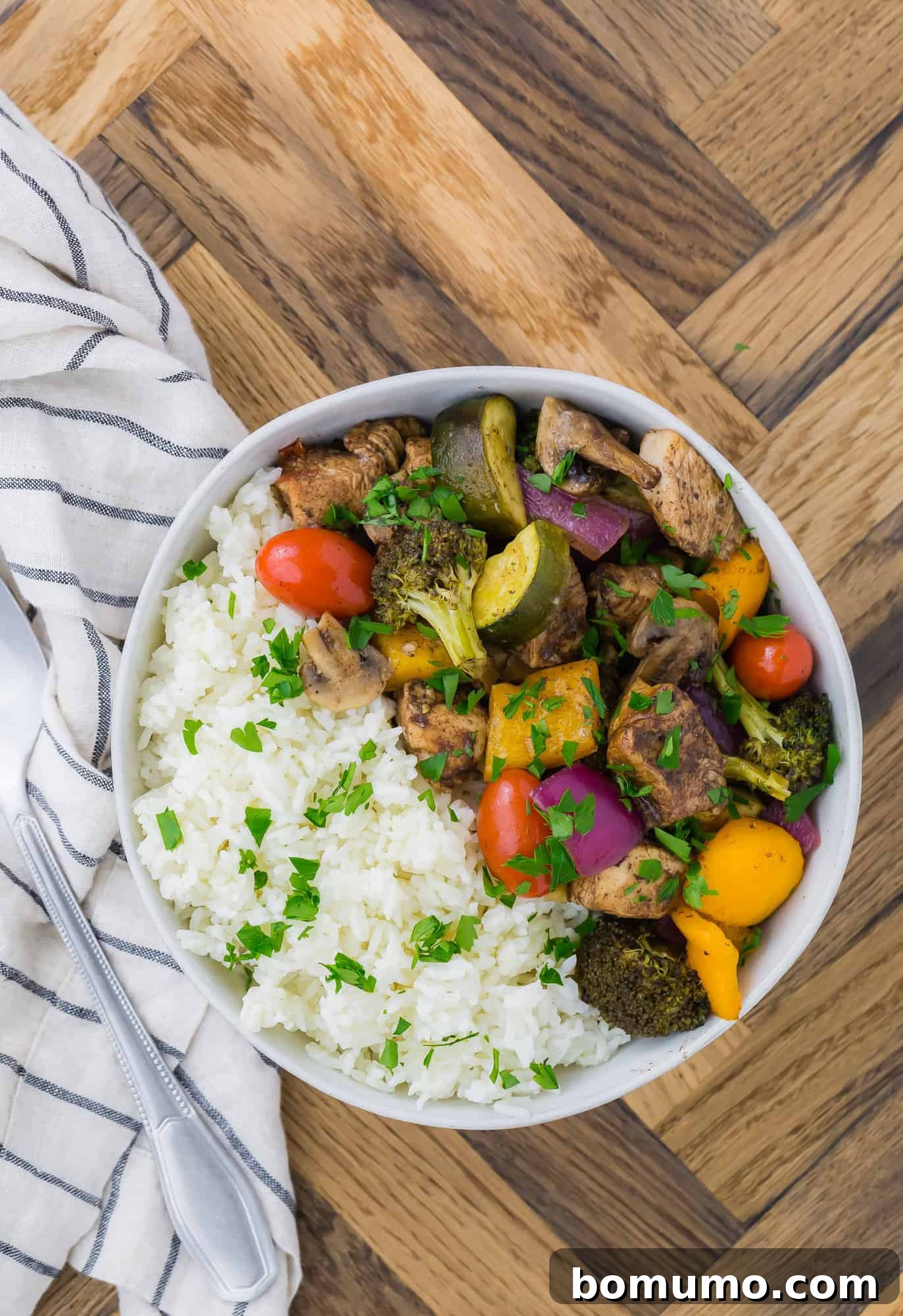 A white bowl filled with rice, honey balsamic chicken, and roasted vegetables.