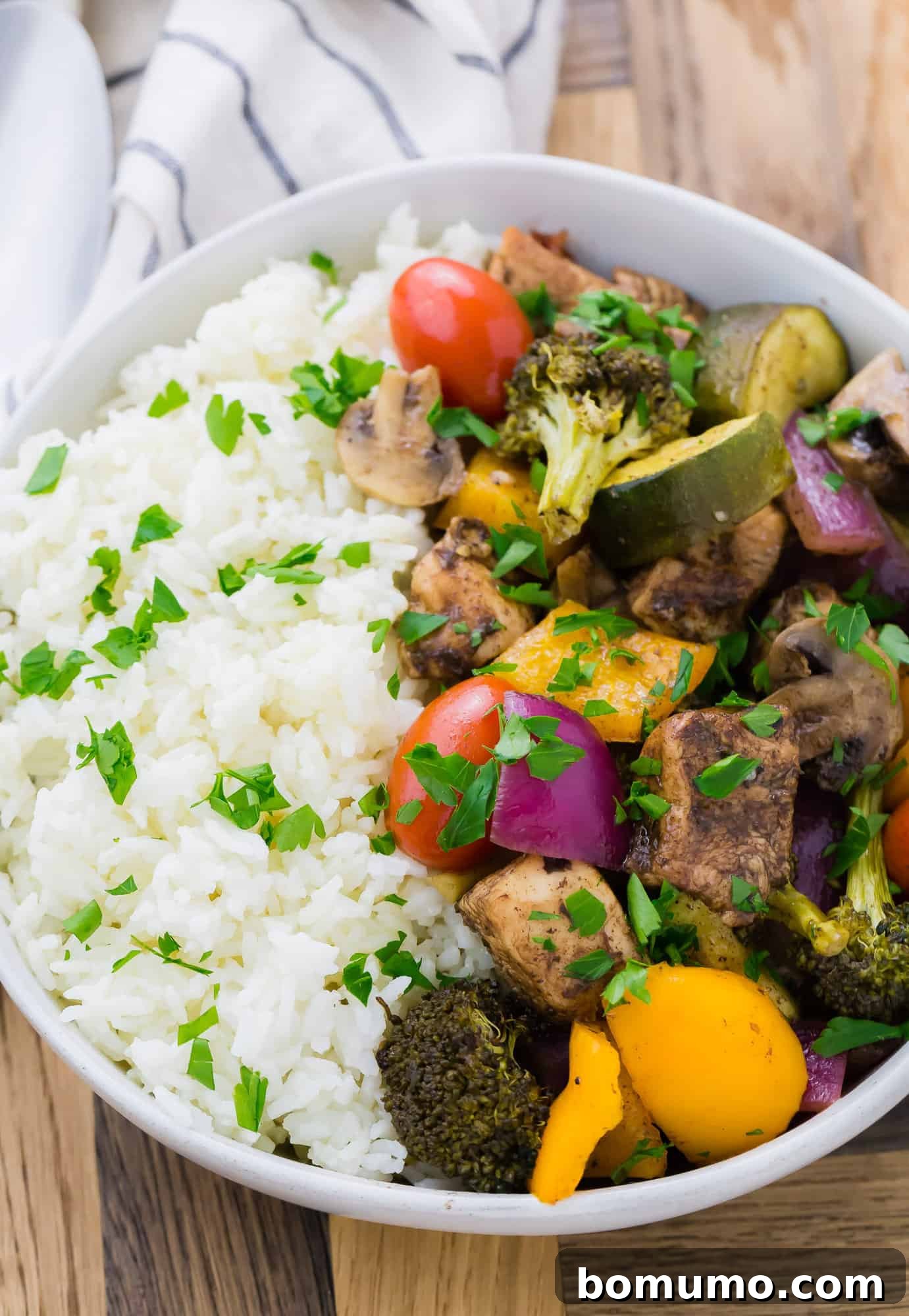 Bowl of rice, chicken, mushrooms, peppers, onions, zucchini, broccoli, and tomatoes.