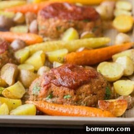 Mini meatloaves and roasted vegetables on sheet pan.