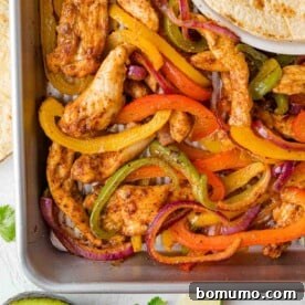 Overhead view of sheet pan fajitas with chicken, peppers, and onions.