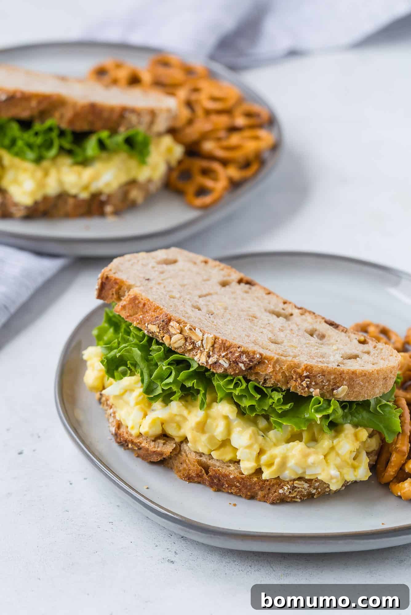 Healthy Egg Salad Makeover 2 Healthy egg salad on whole grain bread, garnished with fresh herbs.