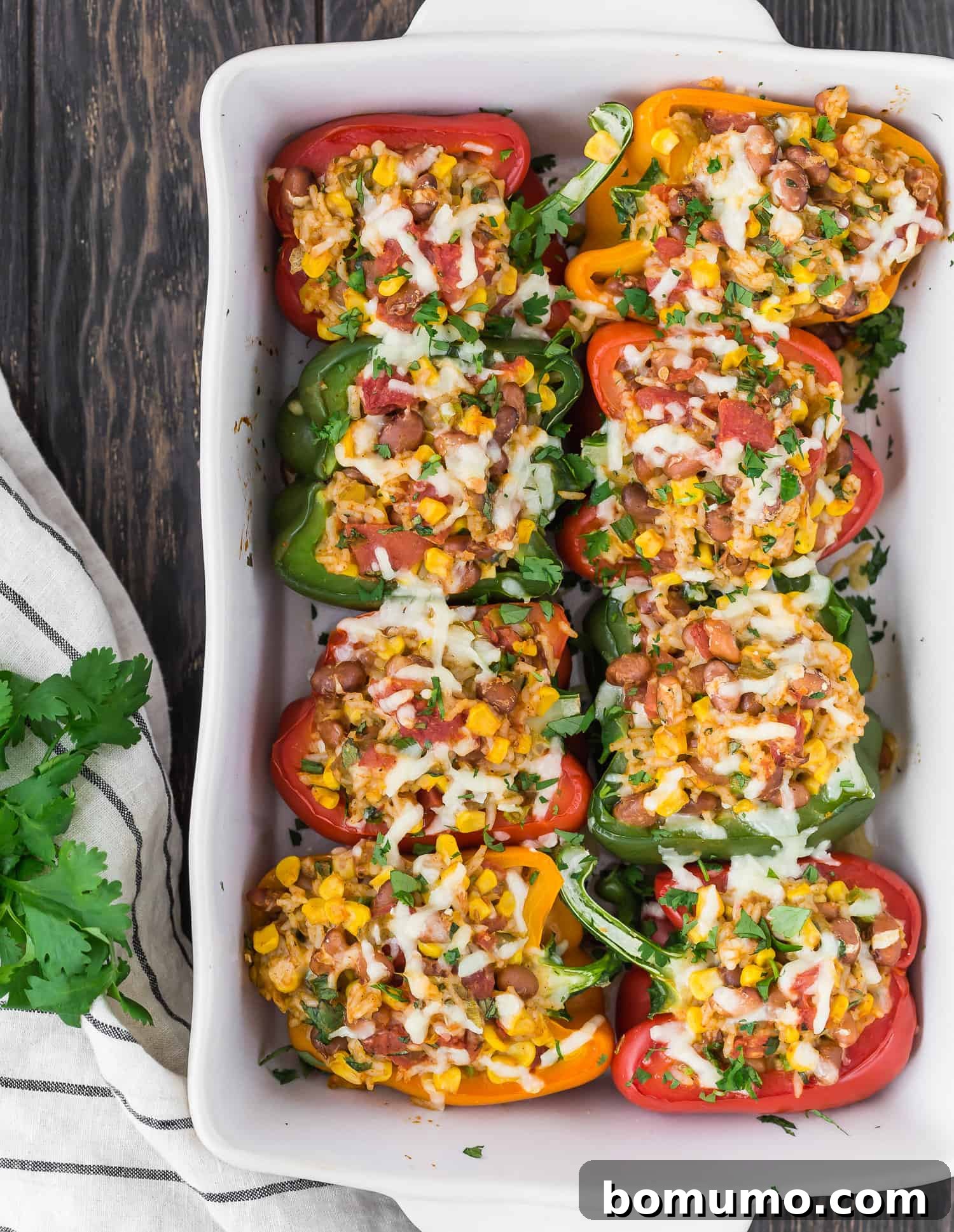 Eight individual vegetarian stuffed bell peppers showcased in a white casserole dish, baked and ready to serve.