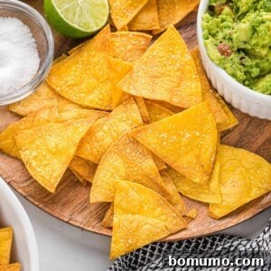 Homemade baked tortilla chips on a rustic wooden platter, ready to be enjoyed with your favorite dip.