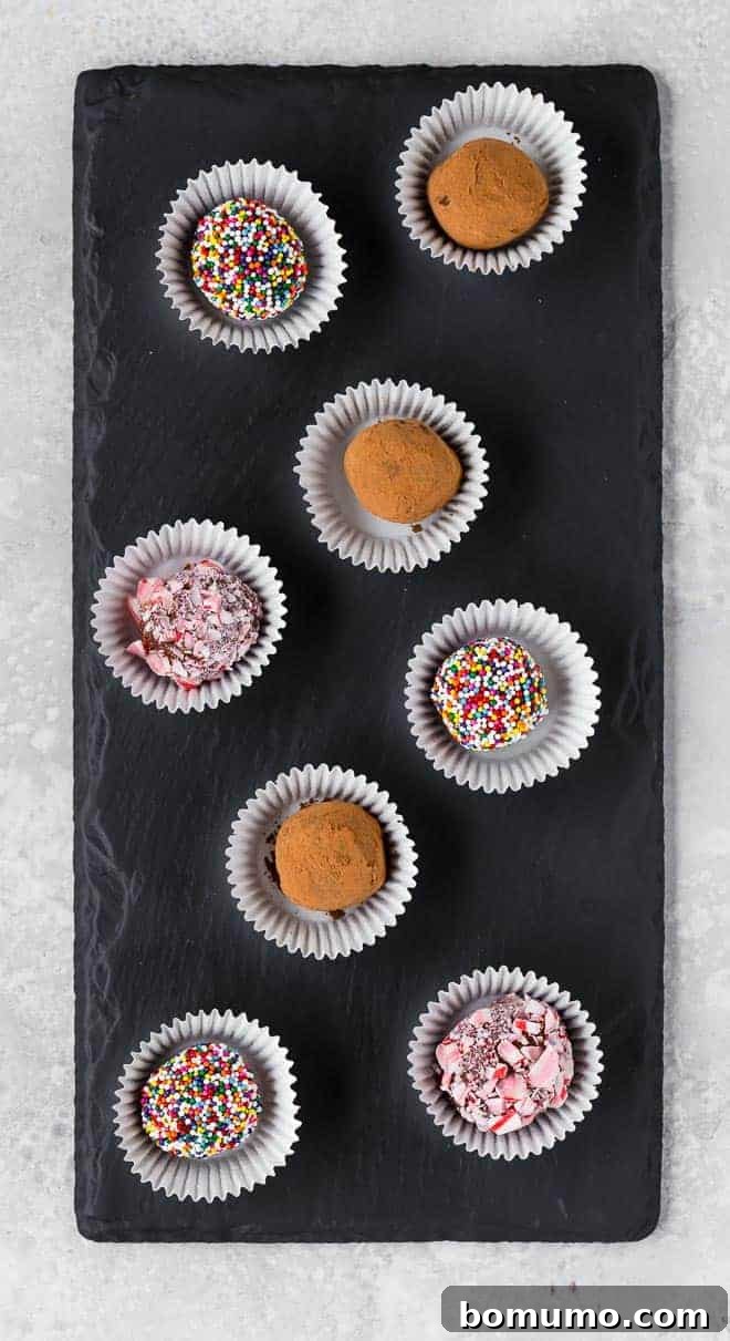 An inviting arrangement of several brigadeiro fudge candies, showcasing various coatings, artfully displayed on a sleek black slate board.